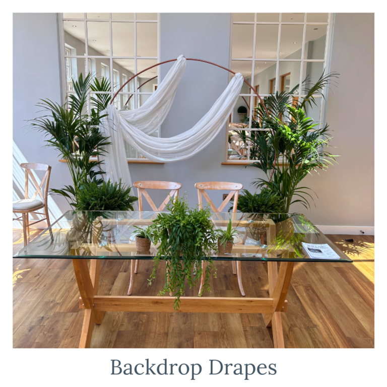 White backdrop drapes styled with greenery for a wedding ceremony backdrop