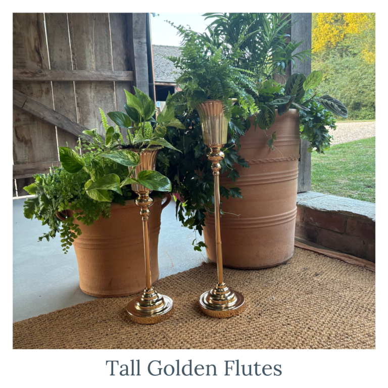 Tall gold flute vases filled with greenery for wedding décor