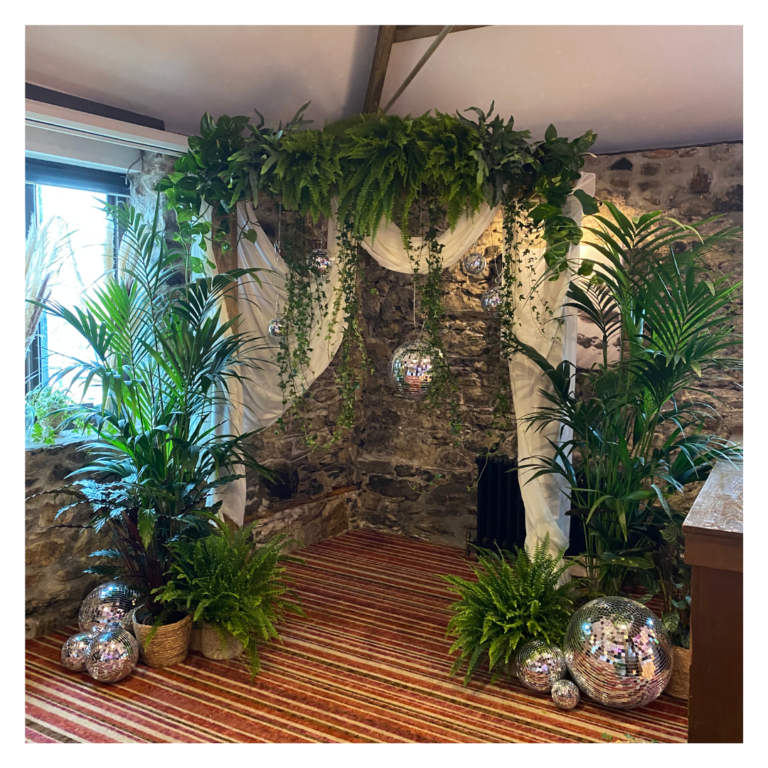 Greenery wedding arch with draped fabric and disco balls in a rustic stone venue