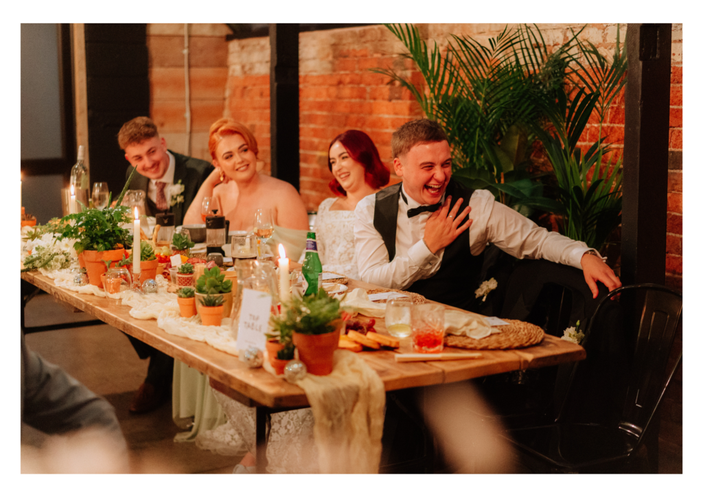 Groom laughing at wedding speech at the head table dressed with terracotta plant pots and live foliage