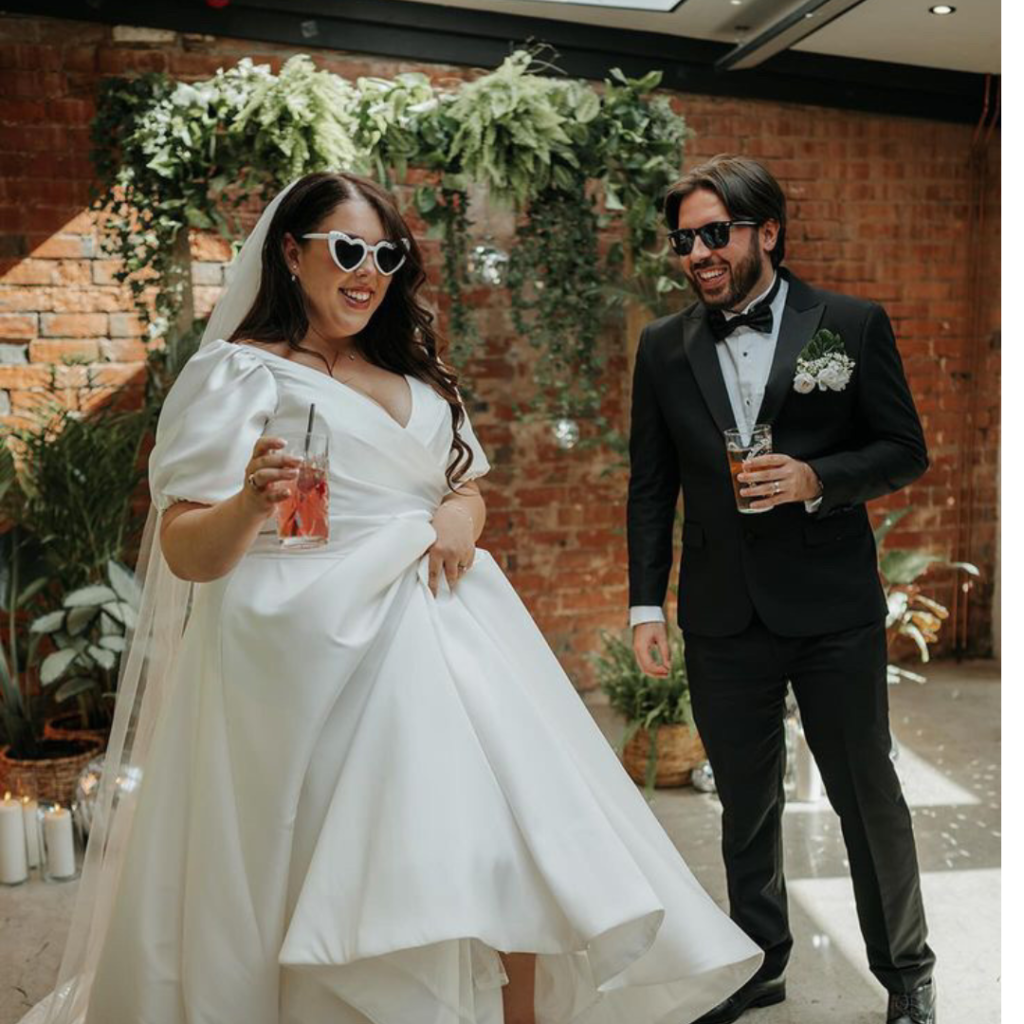 Stylish bride and groom wedding portrait, bride in flowing white gown and groom in black tuxedo, modern urban wedding photography.