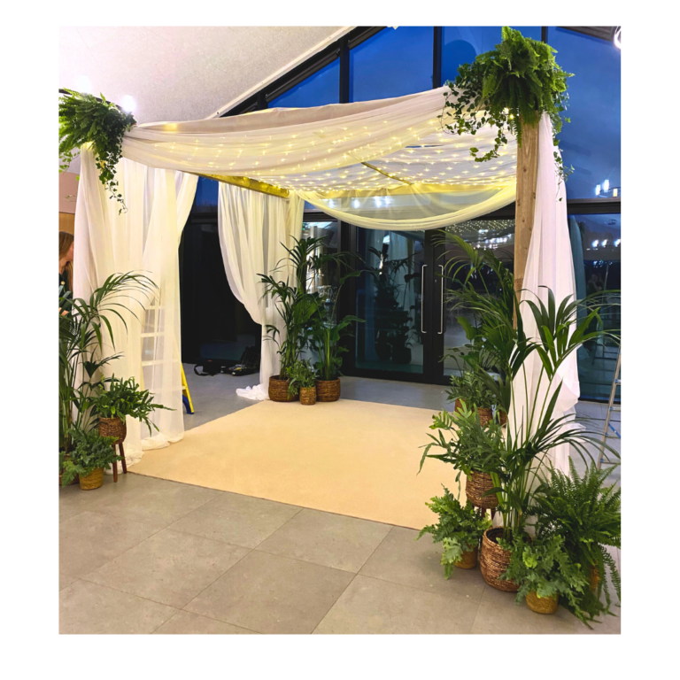 Modern botanical mandap with white drapes, greenery and fairy lights for an Indian wedding ceremony