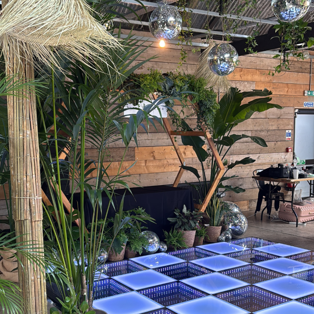 Tropical wedding styling with statement palms, disco balls and illuminated dance floor in industrial venue.